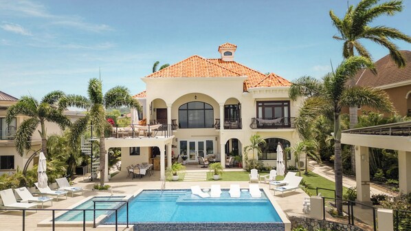A two-story building with a swimming pool, outdoor seating, and palm trees. - Luxury 6-bedroom estate in charming Ocho Rios overlooking the Caribbean Sea (Ocho Rios)