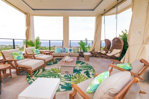 Ein Balkon mit Korbmöbeln, einem runden Tisch und Blick auf das Meer.