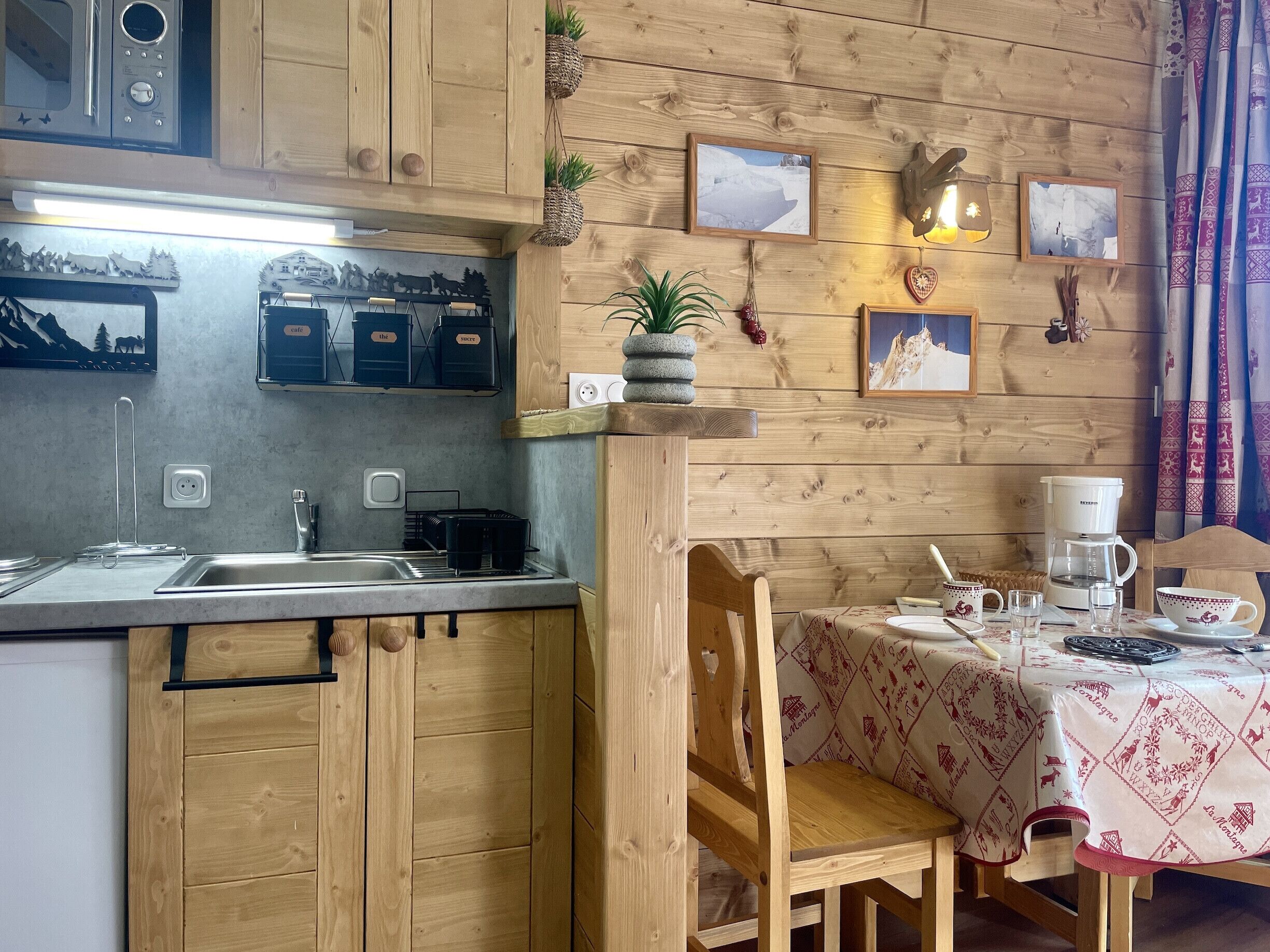 A kitchen with wooden cabinets, a sink, a coffee maker, and a table with a tablecloth.