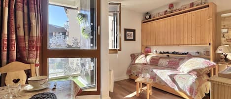 Ein gemütliches Zimmer mit einem Bett, einer Holzkommode, einem Tisch mit Tischdecke und einem Fenster mit Vorhängen.