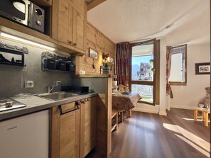 A compact kitchen with wooden cabinets, a built-in microwave, and a sink. - (SO.317) Alpine-style studio, right at the slopes, Les (Les Menuires)