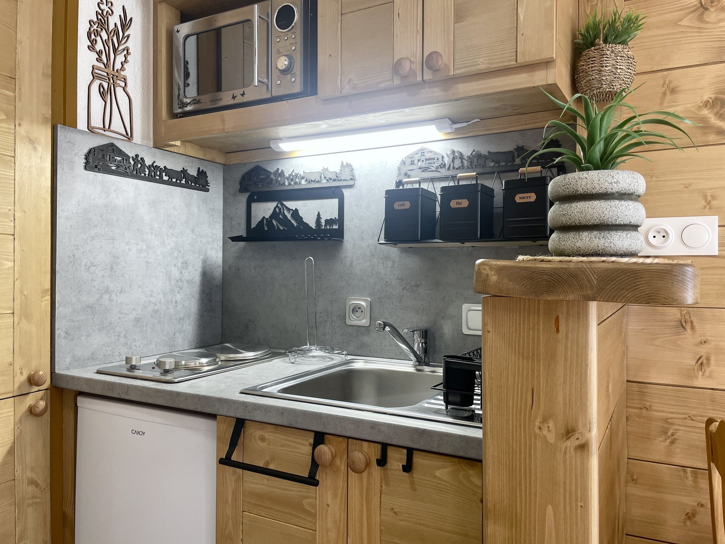 A kitchen with wooden cabinets, a microwave, a sink, and a small refrigerator.