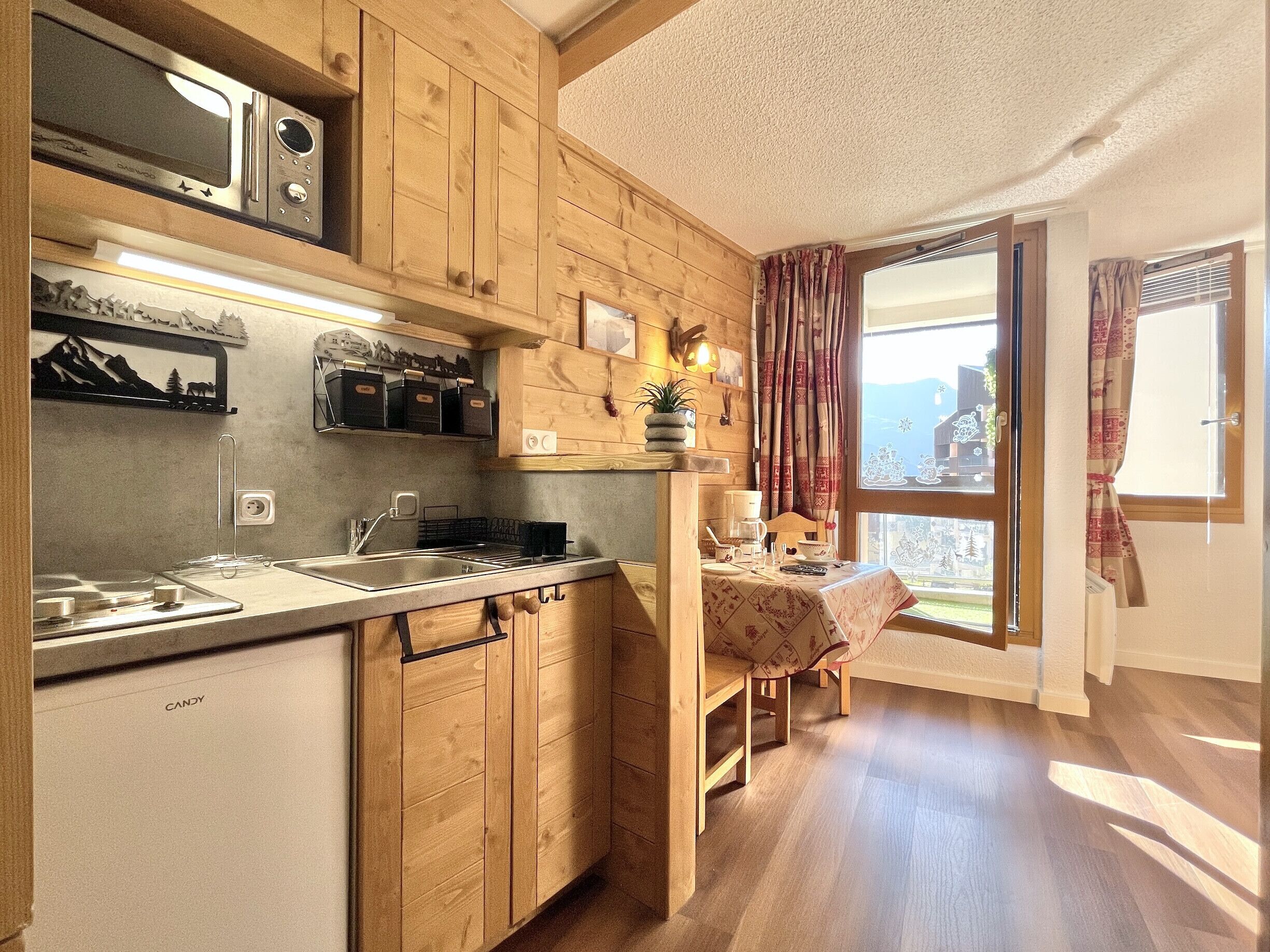 Une cuisine dotée de meubles en bois, d’un four à micro-ondes et d’un coin repas avec une table et des chaises.