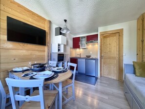 A compact kitchen with a dining area, wooden walls, and a built-in TV. - (BO.421) Comfortable studio, right at the slopes in 3 Vallées (Les Menuires)