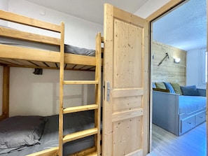 A room with a bunk bed, a wooden ladder, a sliding door, and a bed with multiple pillows. - (BO.421) Comfortable studio, right at the slopes in 3 Vallées (Les Menuires)