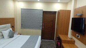 Une chambre d’hôtel avec un lit, une télévision, une armoire et une porte.