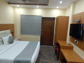 Habitación de hotel con cama, televisión, armario y puerta.