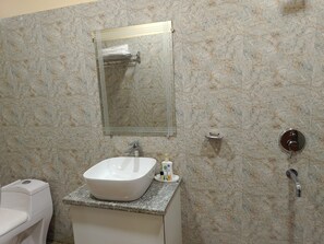 Un baño con lavamanos blanco, un espejo, toallero y un inodoro.