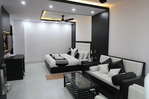 Una habitación de hotel moderna con cama, sofá, mesa de centro de vidrio y televisión.