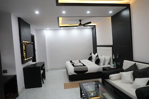 Un dormitorio moderno con cama, sofá, televisor y ventilador de techo.