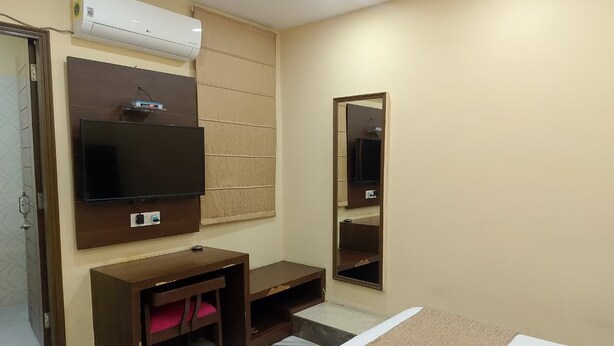 Une chambre d’hôtel comprenant un lit, un bureau avec une chaise, une télévision et un grand miroir.
