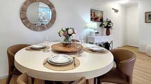 A dining area with a round table, chairs, and a mirror on the wall. - Style & Bright 2BR with leafy balcony & parking (Cammeray)