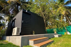 A modern building with a black exterior, a concrete base, and a wooden bench.