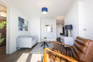 A modern living room with a sofa, a leather chair, a coffee table, a TV, and a lamp. - The Penthouse at No 162 (Birmingham)