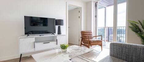 A modern living room with a flat-screen TV, a sofa, a coffee table, and a chair.
