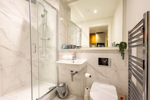 A modern bathroom with a glass-enclosed shower, a sink, and a toilet. - The Penthouse at No 162 (Birmingham)
