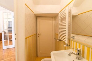Ein Badezimmer mit einem weißen Waschbecken, einem Spiegel und einer Tür.