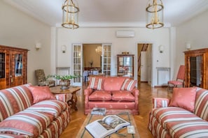Ampla sala de estar com um sofá grande, uma mesa de centro e um candelabro.