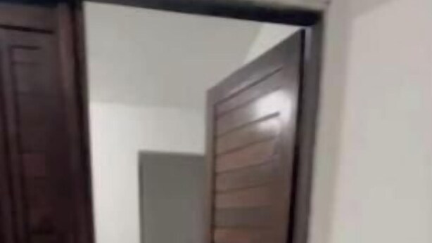 Un pasillo con puerta de madera y suelo de baldosas.