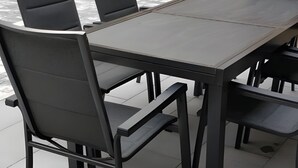 Eine Terrasse im Freien mit einem rechteckigen Tisch und sechs Stühlen.