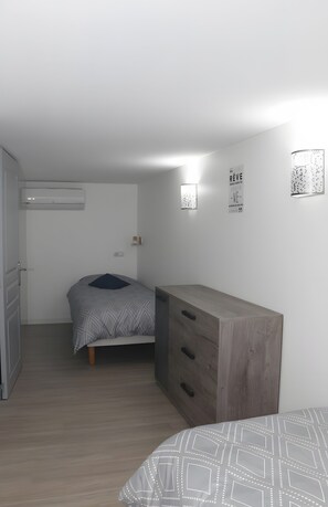 A bedroom with a bed, a dresser, and a wall-mounted air conditioner.