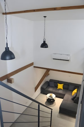 A modern living room with a staircase, a sofa set, and a coffee table.