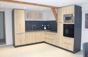 A modern kitchen with wooden cabinets, a black countertop, a built-in microwave, and an oven.