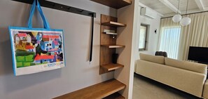 Ein Zimmer mit einer Couch, Holzregalen und einer blauen Tasche mit buntem Muster.