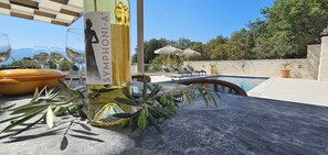 A poolside area with a table, a bottle of wine, and lounge chairs. - Eliá Luxury Villa with a Jacuzzi and Privacy, in the Heart of Crete (Kalonichti)