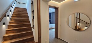 Eine Treppe mit Holzboden und Geländer führt zu einem Schlafzimmer mit Bett und Deckenventilator.