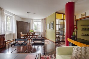 Een ruime woonkamer met een eethoek, een rode zuil en een boekenkast.
