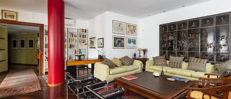 A living room with a red pillar, two sofas, a coffee table, and a bookshelf.