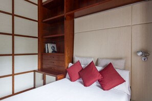 A hotel room with a bed, a wooden wardrobe, and a bedside table. - Aventino Luxury Amazing Apartment (Roma)