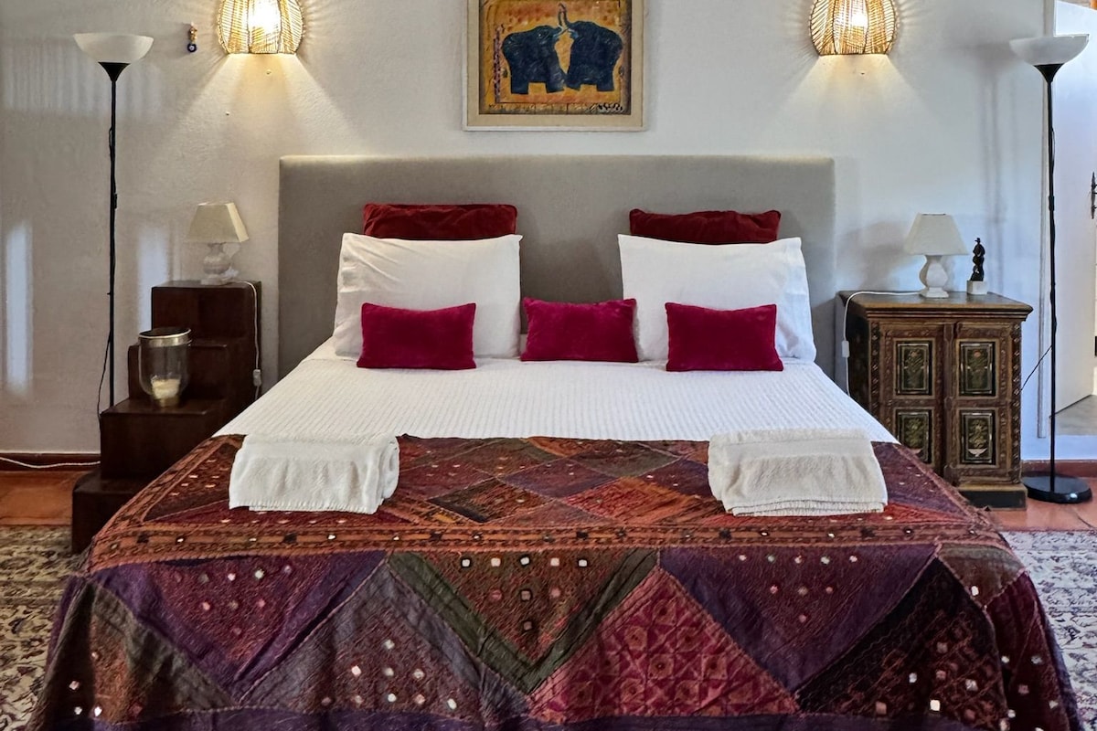 Une chambre d’hôtel avec un grand lit, deux lampes de chevet, une table de chevet, un tapis décoratif et un tableau au mur.