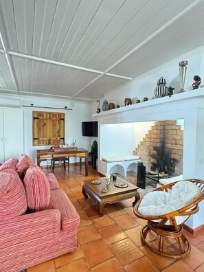 A living room with a fireplace, a dining area, and a seating area with a sofa and chairs.