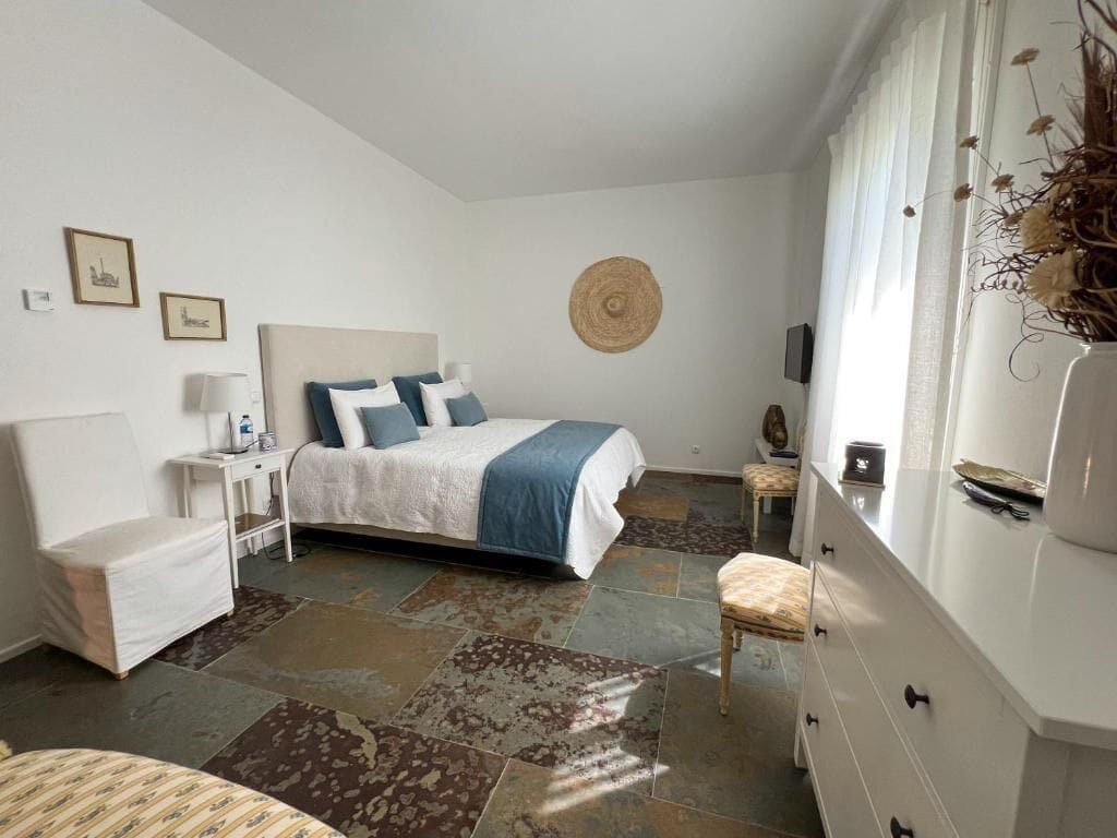 A bedroom with a bed, bedside table, lamp, and a decorative wall hanging.