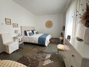 A bedroom with a bed, bedside table, lamp, and a decorative wall hanging.