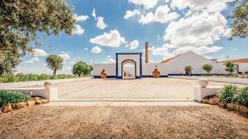 Un edificio con un arco central, una chimenea y un área de entrada pavimentada.