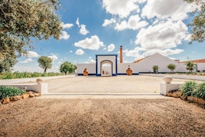 A building with a central archway, a chimney, and a paved entrance area. - Herdade Terra Rica (Alcacer do Sal)