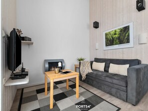 Ein modernes Wohnzimmer mit einem grauen Sofa, einem Holztisch, einem Flachbildfernseher, einem Kamin und einem gerahmten Naturfoto an der Wand.