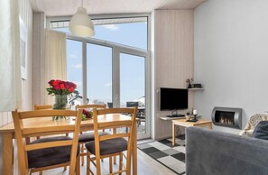 Ein modernes Wohnzimmer mit Essbereich, Kamin und großem Fenster mit Aussicht.