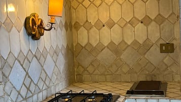 A kitchen with a gas stove, a wall-mounted light fixture, and a tiled backsplash.