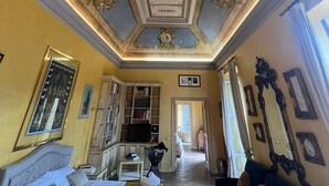 Quarto de hotel com cama, televisão, estante e área de refeições.
