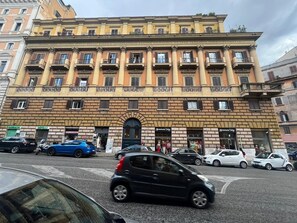 Un edificio de varios pisos con estilo arquitectónico clásico, que presenta una entrada central con un amplio arco y varios balcones.
