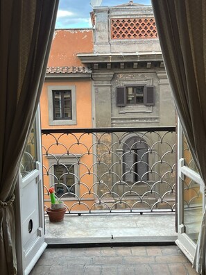 A balcony with a metal railing, a potted plant, and a view of adjacent buildings. - antico suites roma (Roma)