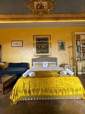 Una habitació amb un llit, un sofà, una prestatgeria i un quadre a la paret.