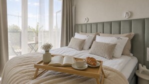 A bedroom with a bed, bedside tables, a window with curtains, and a view of the outside. - Portovo Gdansk City Vibes Suites (Gdańsk)
