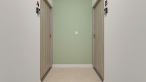 A hallway with two wooden doors, each marked with a letter, leading to a room. - Portovo Gdansk City Vibes Suites (Gdańsk)