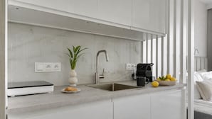 A modern kitchen with a built-in sink, a coffee machine, and a bowl of lemons. - Portovo Gdansk City Vibes Suites (Gdańsk)