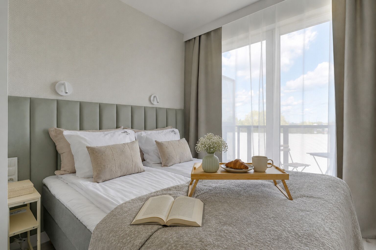 Quarto com cama, mesa de cabeceira e janela com vista.